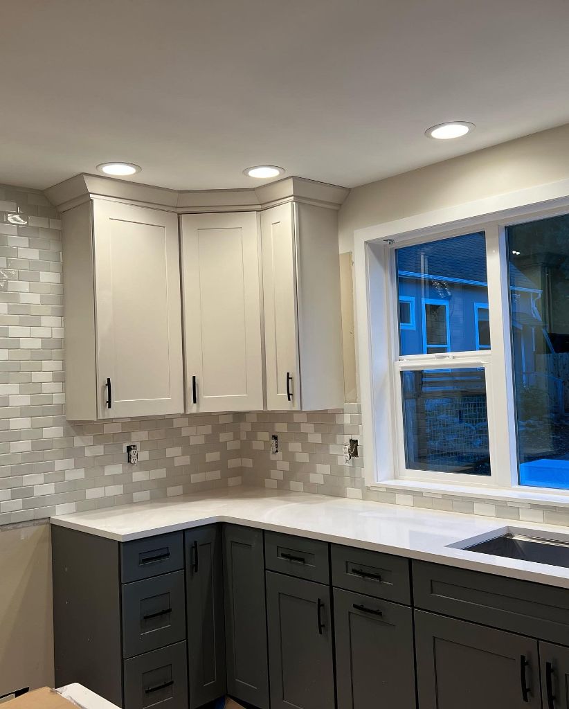 Kitchen remodel in progress — two-tone cabinets and tile backsplash